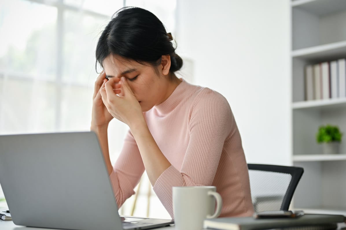 Stressed Asian businesswoman suffering from headaches while concerned about her work.